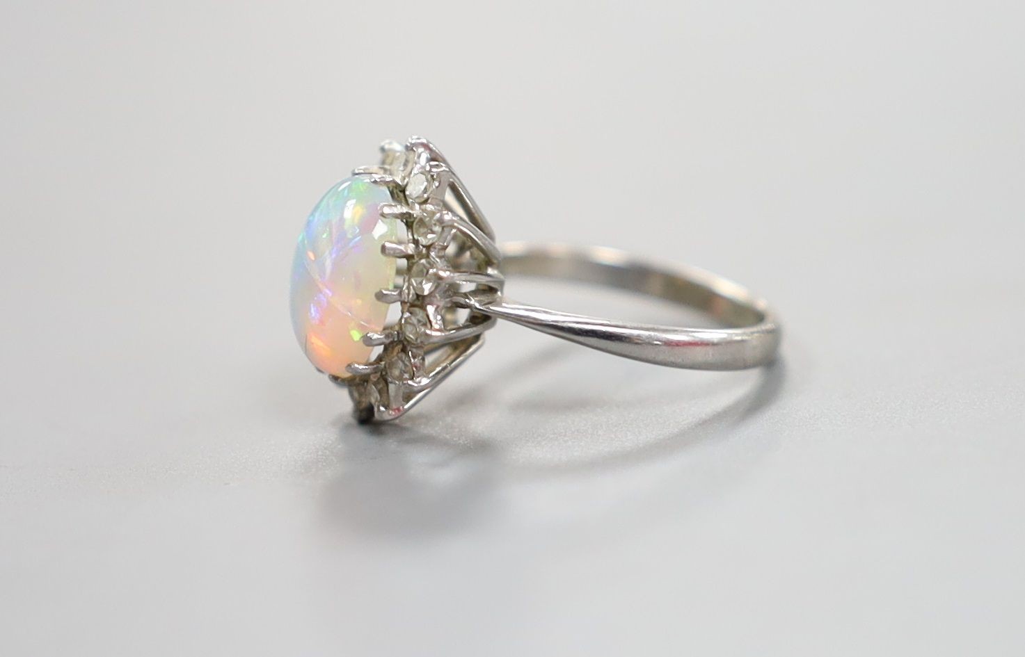 An 18ct white metal, white opal and diamond set oval cluster ring, size G, gross weight 2.9 grams.